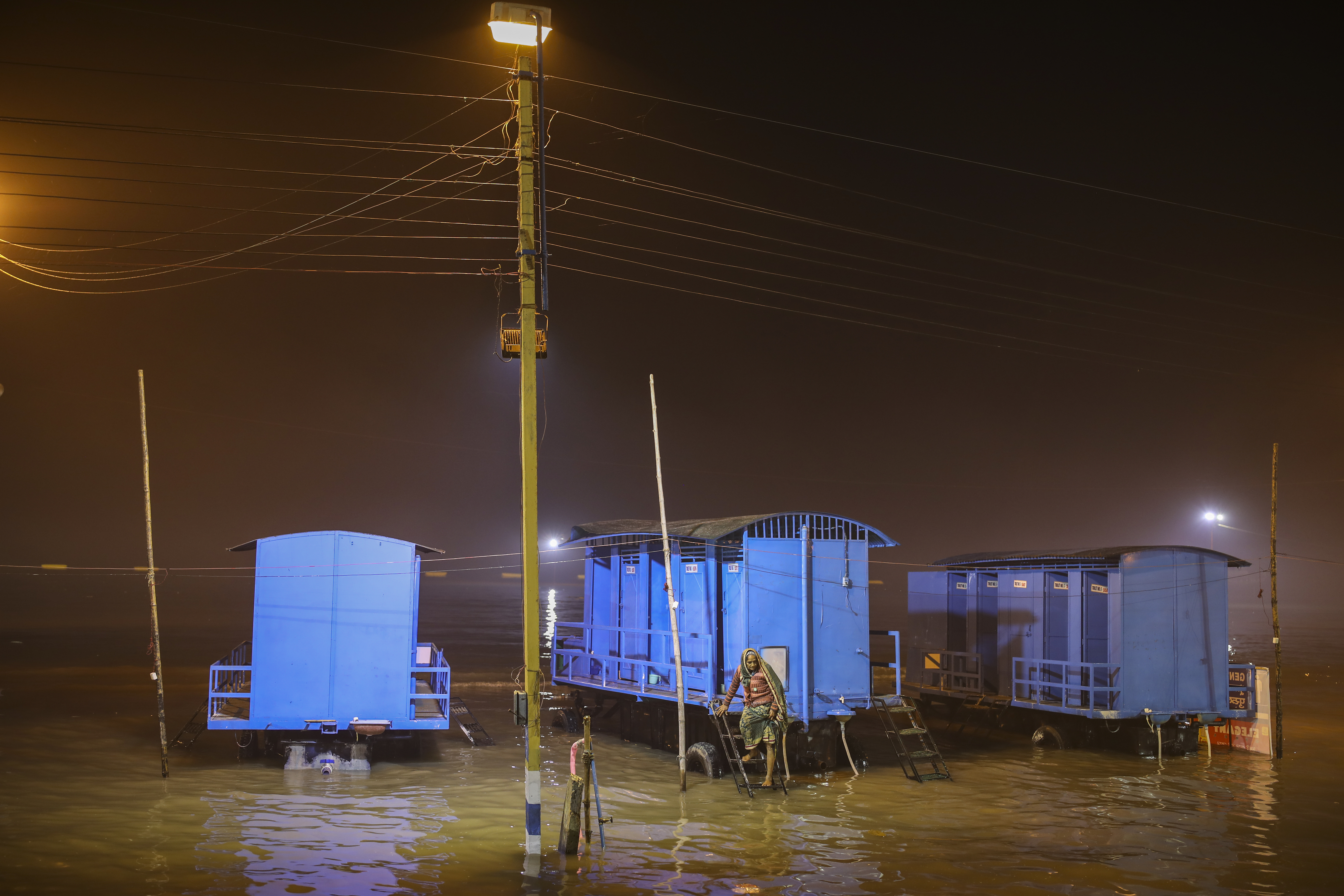 A pilgrim is stranded on a mobile toilet after high tide submerged the camping area for pilgrims on the eve of Makar Sankranti festival on Sagar Island.