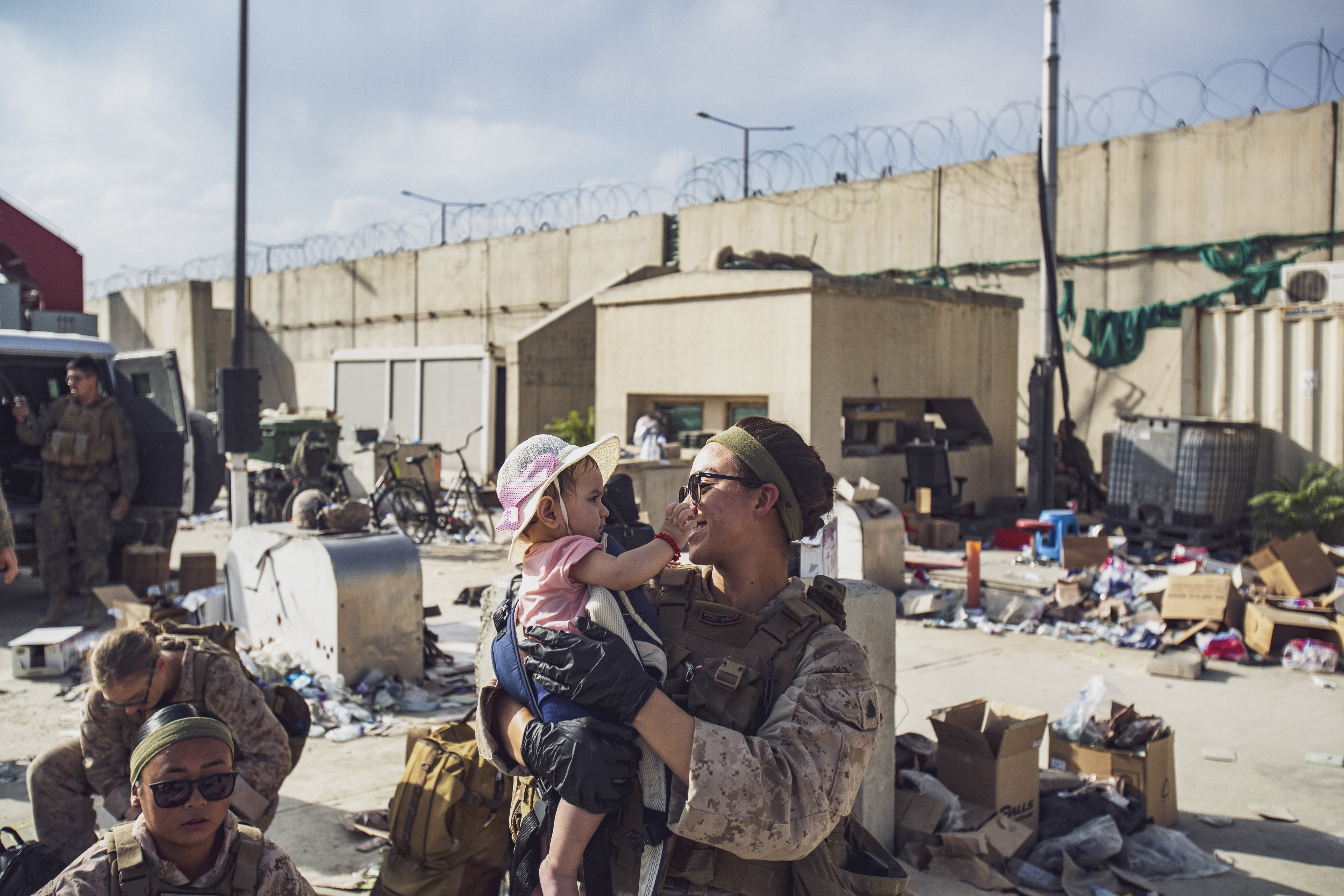 a Marine assigned to Special Purpose Marine Air-Ground Task Force-Crisis Response-Central Command holds a child while her mother is searched at Hamid Karzai International Airport, in Kabul, Afghanistan
