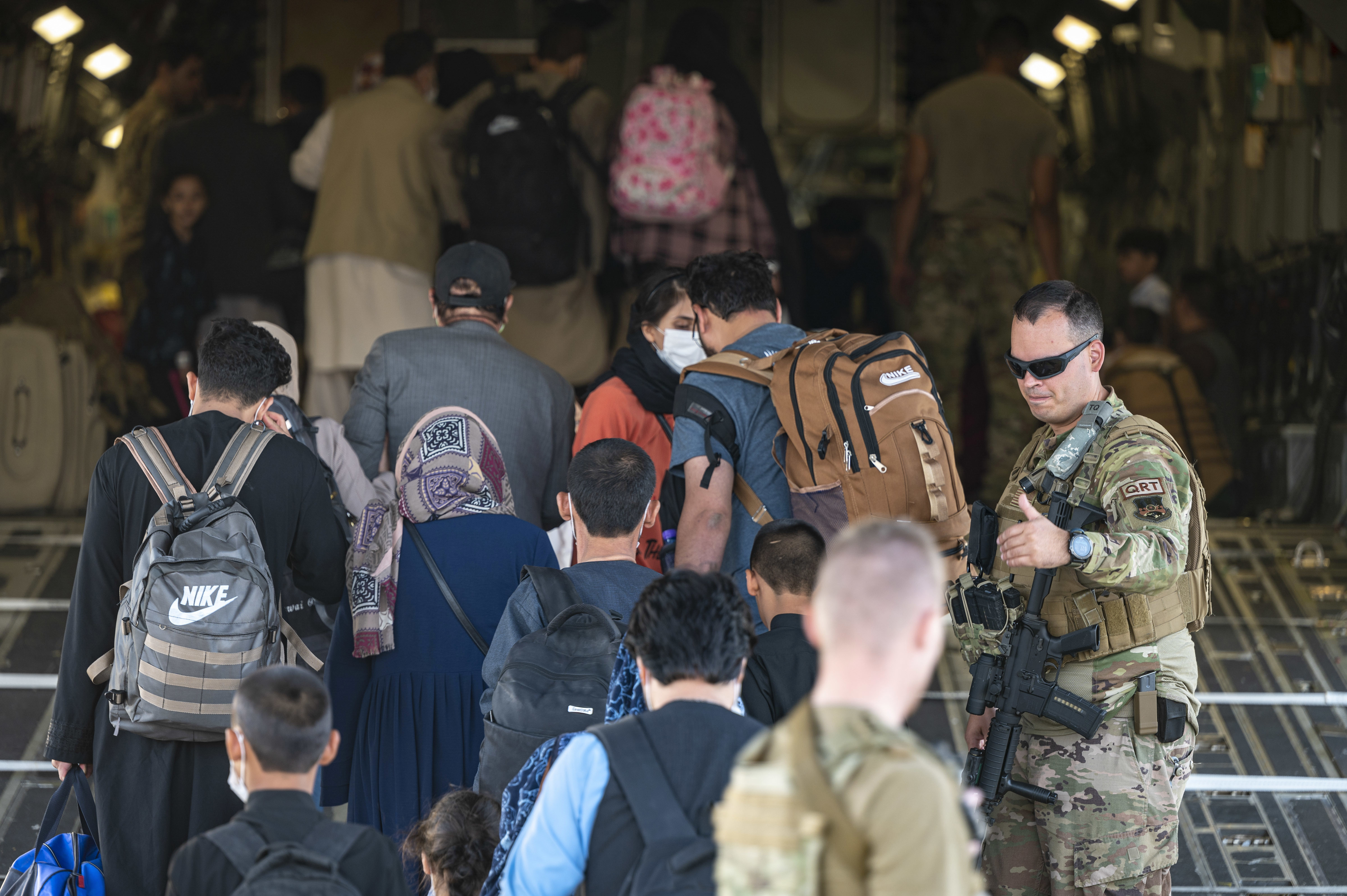 U.S. Air Force airmen guide evacuees aboard a U.S. Air Force C-17 Globemaster III at Hamid Karzai International Airport