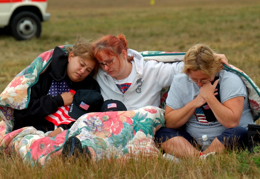 In this Wednesday, Sept. 11, 2002 file photo, from left, Shannon Barry, Lisa Starr and Michelle Wagner, all of Hershey, Pa., comfort each other as they listen to a memorial service for victims of Flight 93 near Shanksville, Pa. President Bush will lay a wreath at the crash site later in the day to mark the anniversary of the terrorist attacks.