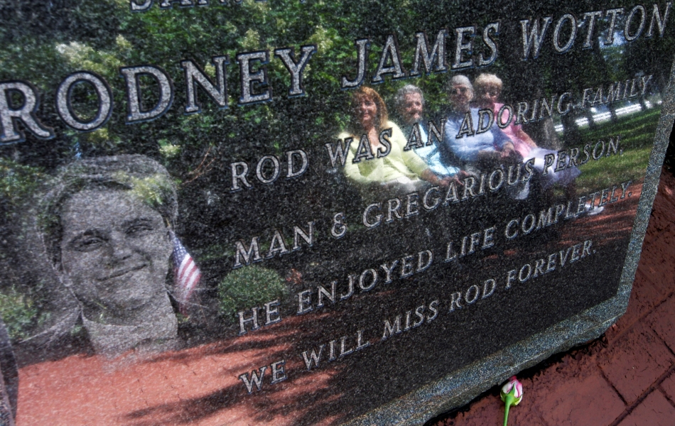 In this Tuesday, Sept. 11, 2012 file photo, Pat Wotton, left, is reflected in a memorial to her husband Rodney James Wotton, as she sits with Dorothy Greene, second left, Jean Wotton, Rodney's mother, and Eunice Saporito, right, in Middletown, N.J. The marker for Rodney Wotton is one of 37 in the Middletown World Trade Center Memorial Gardens for those from the town in central New Jersey, who died in the attack on the World Trade Center in 2001.