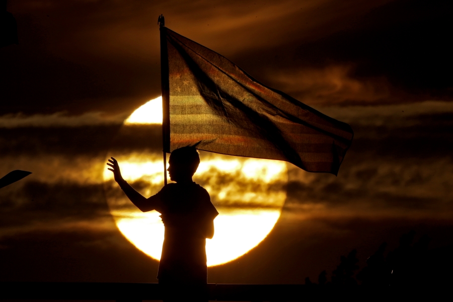 In this Wednesday, Sept. 11, 2019 file photo, a boy waves to passing motorists to commemorate the anniversary of the Sept. 11 terrorist attacks from an overpass on Interstate 35 near Melvern, Kan. Area residents began manning the bridge with flags and waving to motorists on the anniversary in 2002 and have done it ever since.