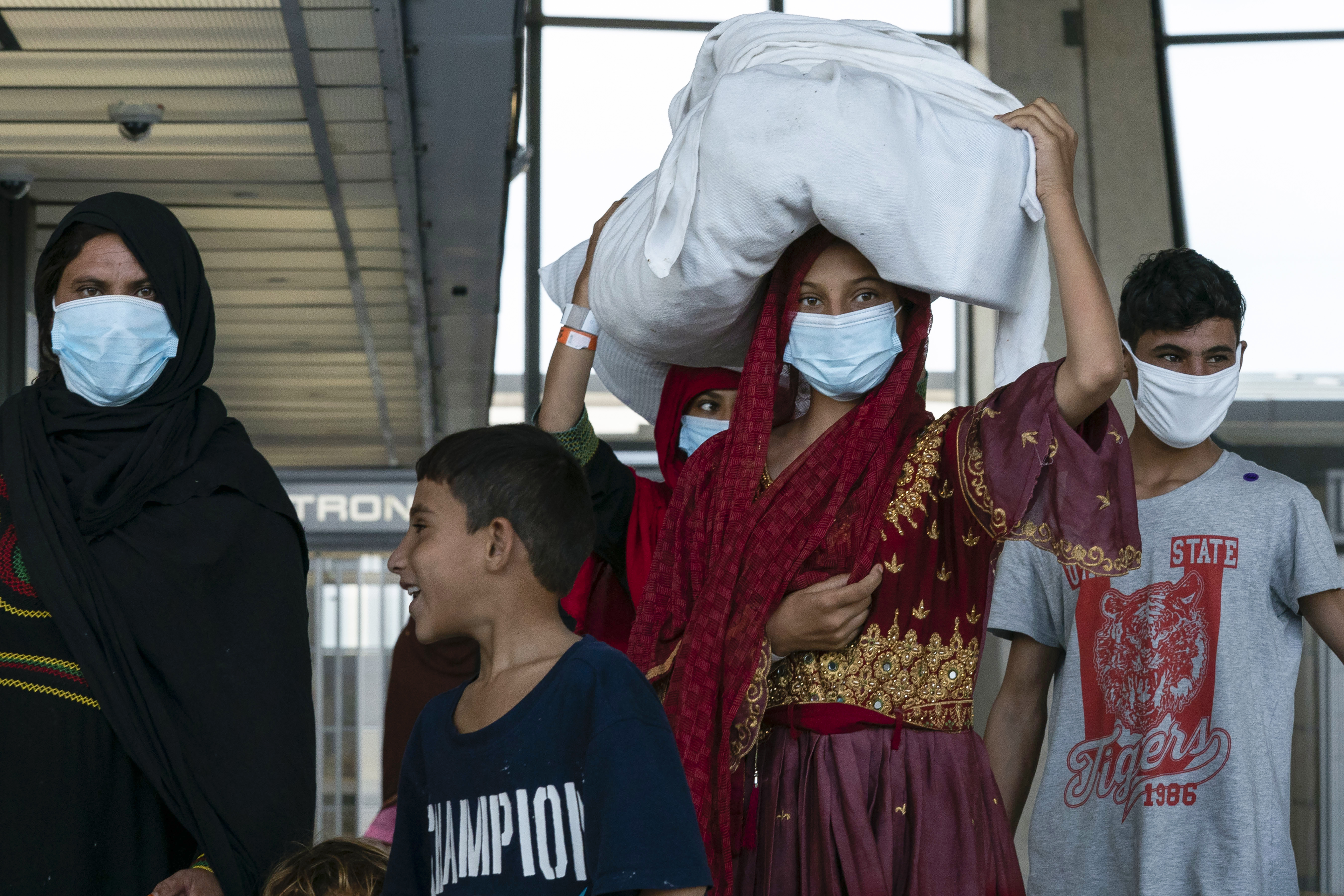 People evacuated from Kabul, Afghanistan, walk through the terminal before boarding a bus after they arrived at Washington Dulles International Airport, in Chantilly, Va., on Monday.