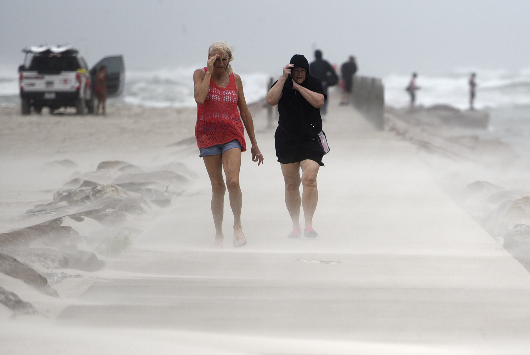 People shield their faces from wind and sand ahead of Tropical Storm Nicholas