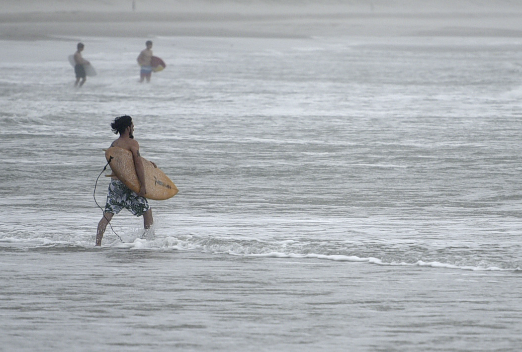 Surfers are seen ahead of Tropical Storm Nicholas