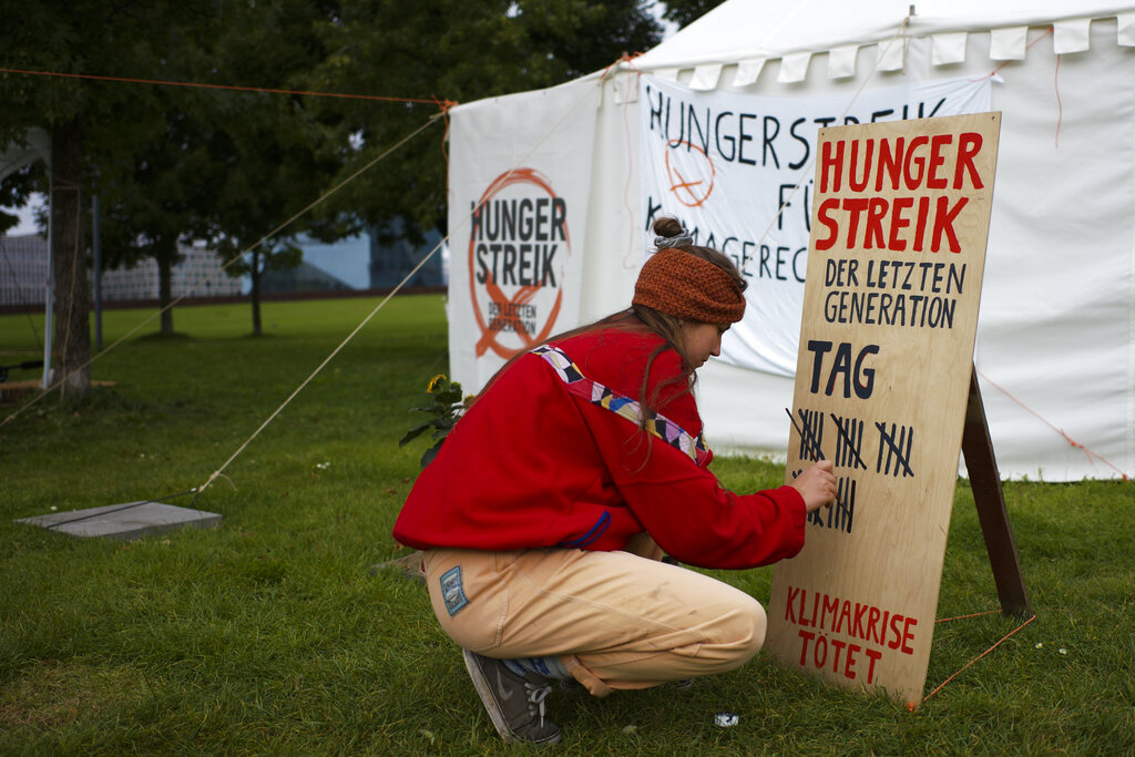 Climate activist Carla Hinrichs makes a line on a wooden board to count the days a small camp of climate activists have been in a hunger strike, near the chancellery in Berlin, Wednesday, Sept. 22, 2021. With the hunger strike the climate activists hope to pressure candidates for chancellor of Germany into meeting them for a debate about the climate crisis ahead Sunday's general election. For the first time in Germany's history, climate change is a central issue of an election campaign, overwhelmingly so for the young generation.