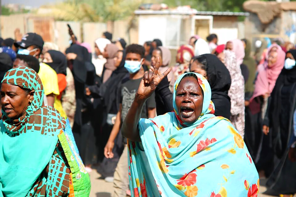 Pro-democracy protesters flash the victory sign as they take to the streets to condemn a takeover by military officials, in Khartoum, Sudan, Monday Oct. 25, 2021