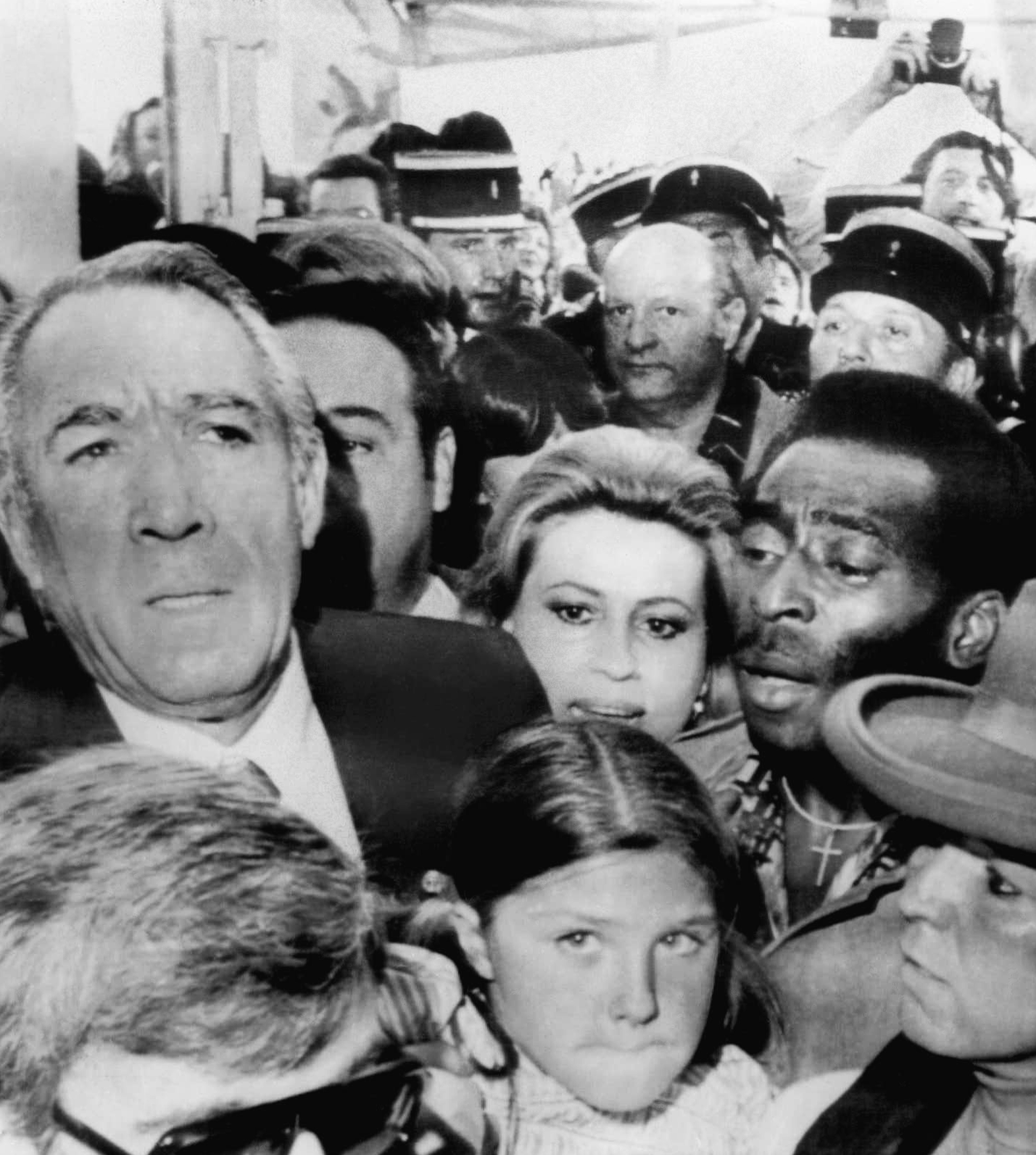 Actor Anthony Quinn, left, his wife Iolanda and Brazilian soccer star Pele, right, make their way through a crowd to attend the showing of the film Pele, directed by Francois Reichenbach and in which Pele stars, at the Cannes film festival in Cannes, France, May 18, 1977.