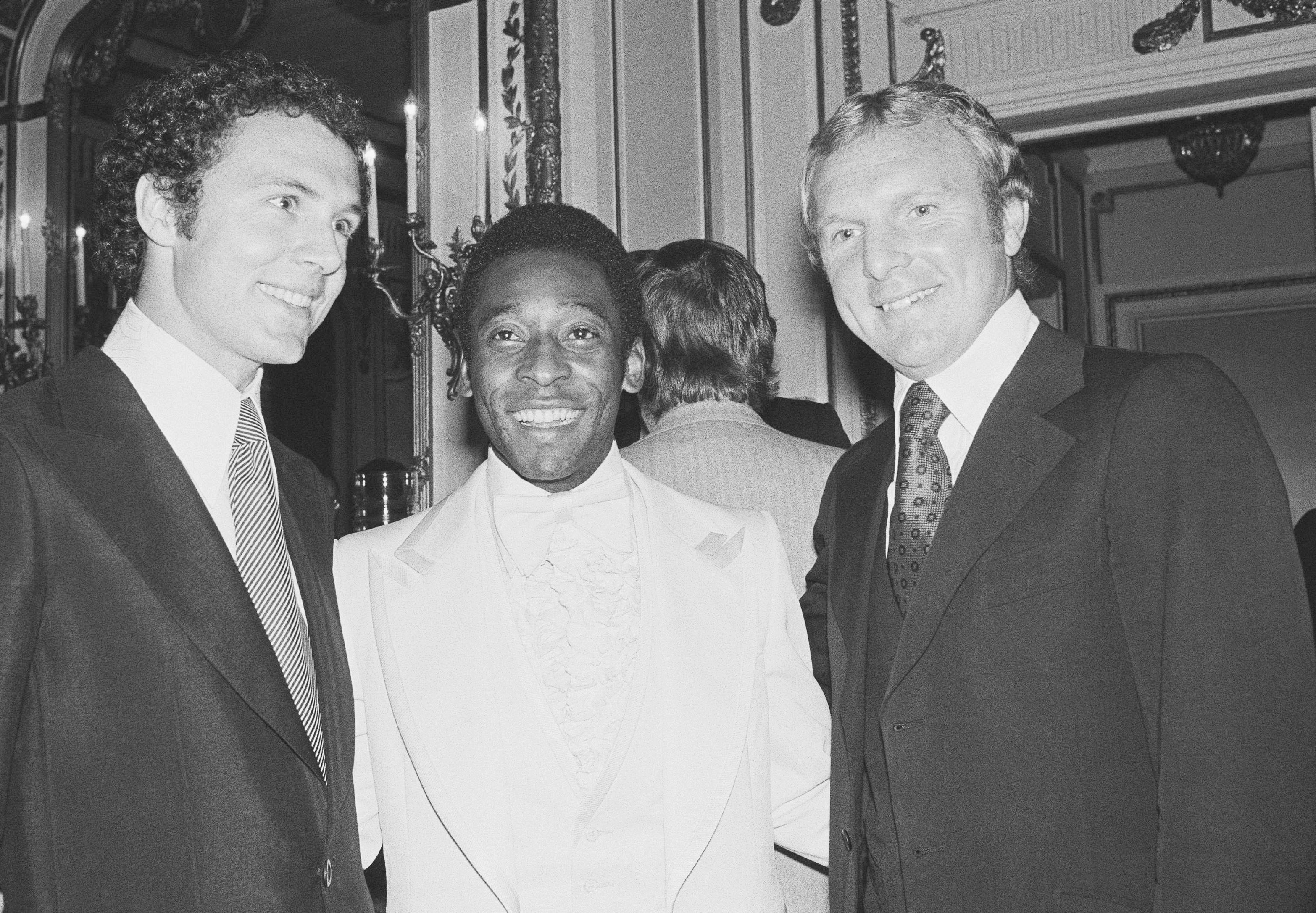 Soccer star Pele, center, poses with two other soccer greats: at left, Cosmos teammate and captain of the 1974 World Cup team from West Germany, Franz Beckenbauer, and Bobby Moore, captain of England's 1966 World Cup soccer team. The occasion was a dinner given for Pele, Sept. 27, 1977 in the Plaza Hotel in New York.