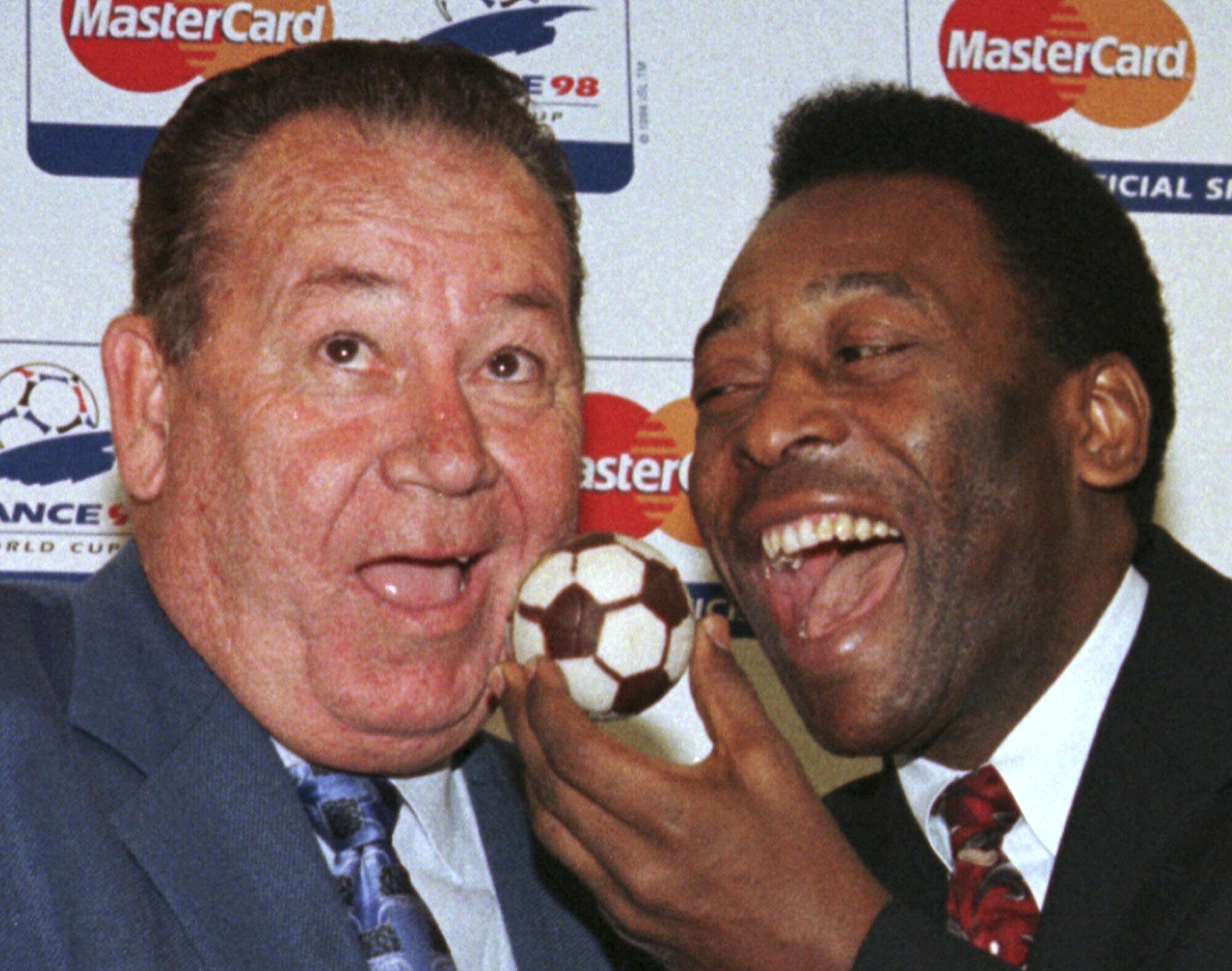 Soccer legend Pele, of Brazil, feeds French soccer legend Just Fontaine, left, a soccer ball cake Sunday, July 5, 1998 in Paris.