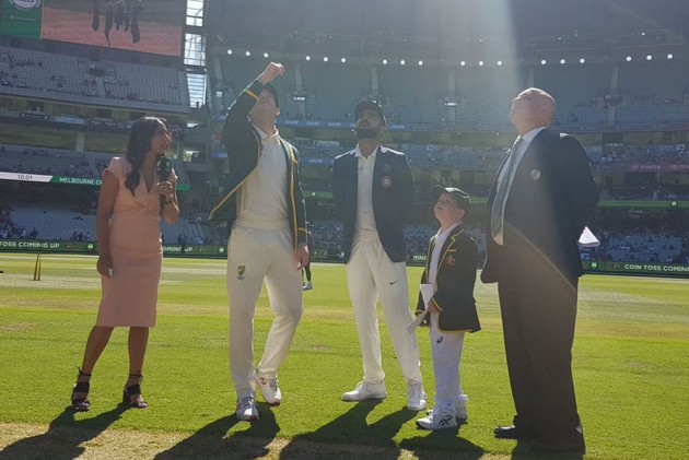 Tim Paine flips the coin as Virat kohli looks on.