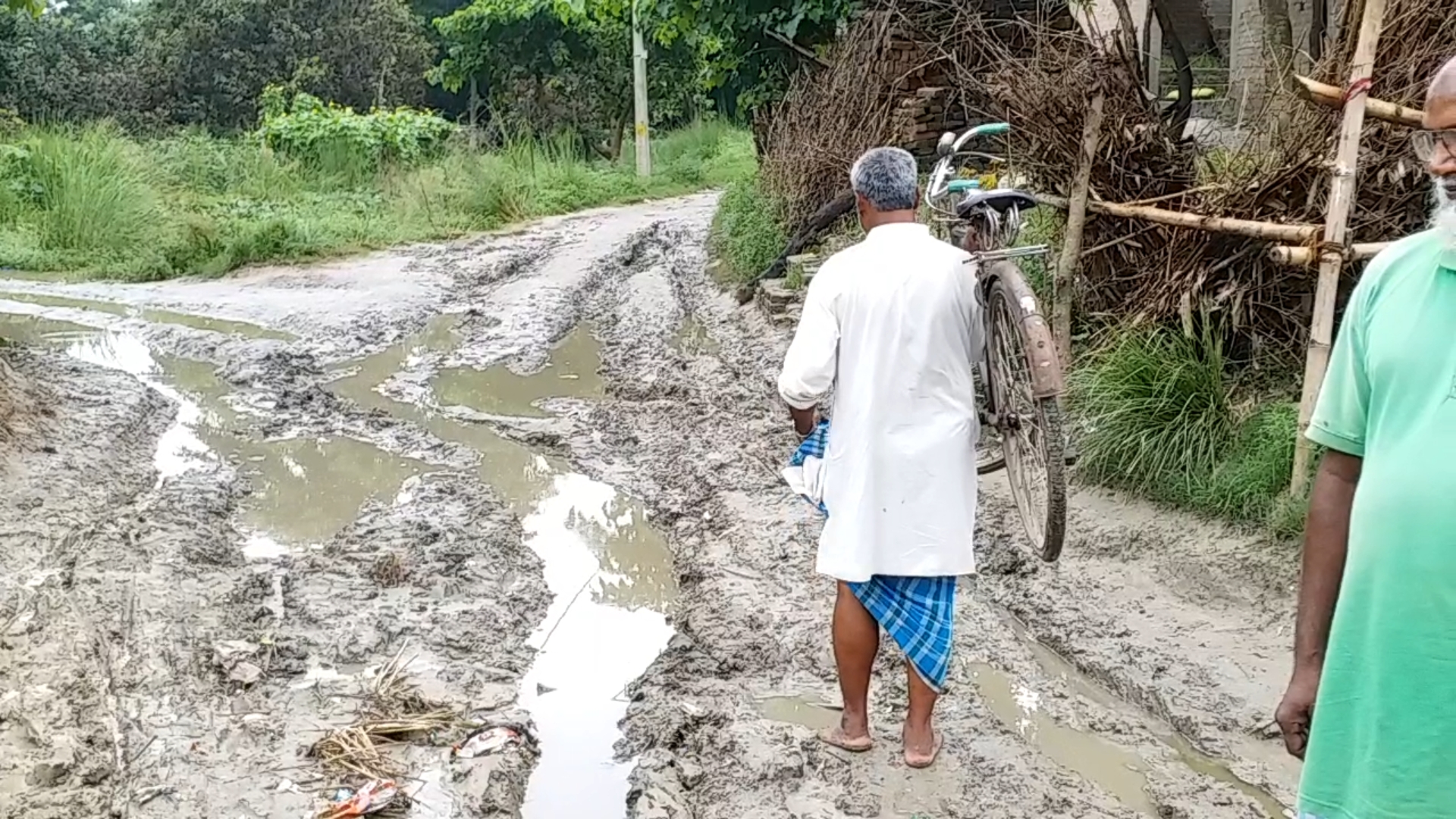 कंघे पर साइकिल रखकर सड़क पार करते लोग