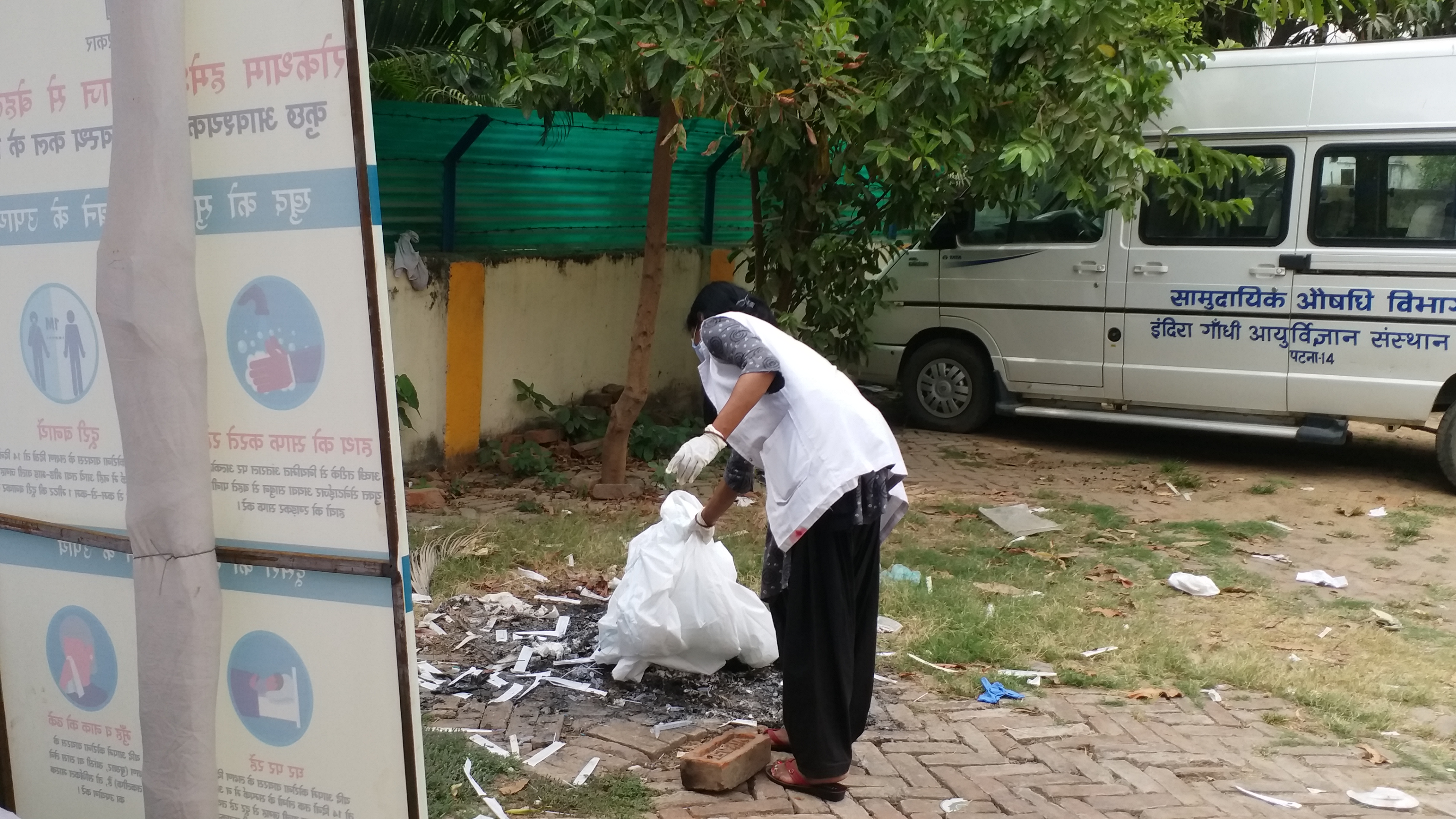 An auxiliary nurse midwife while lilting fire to the medical waste