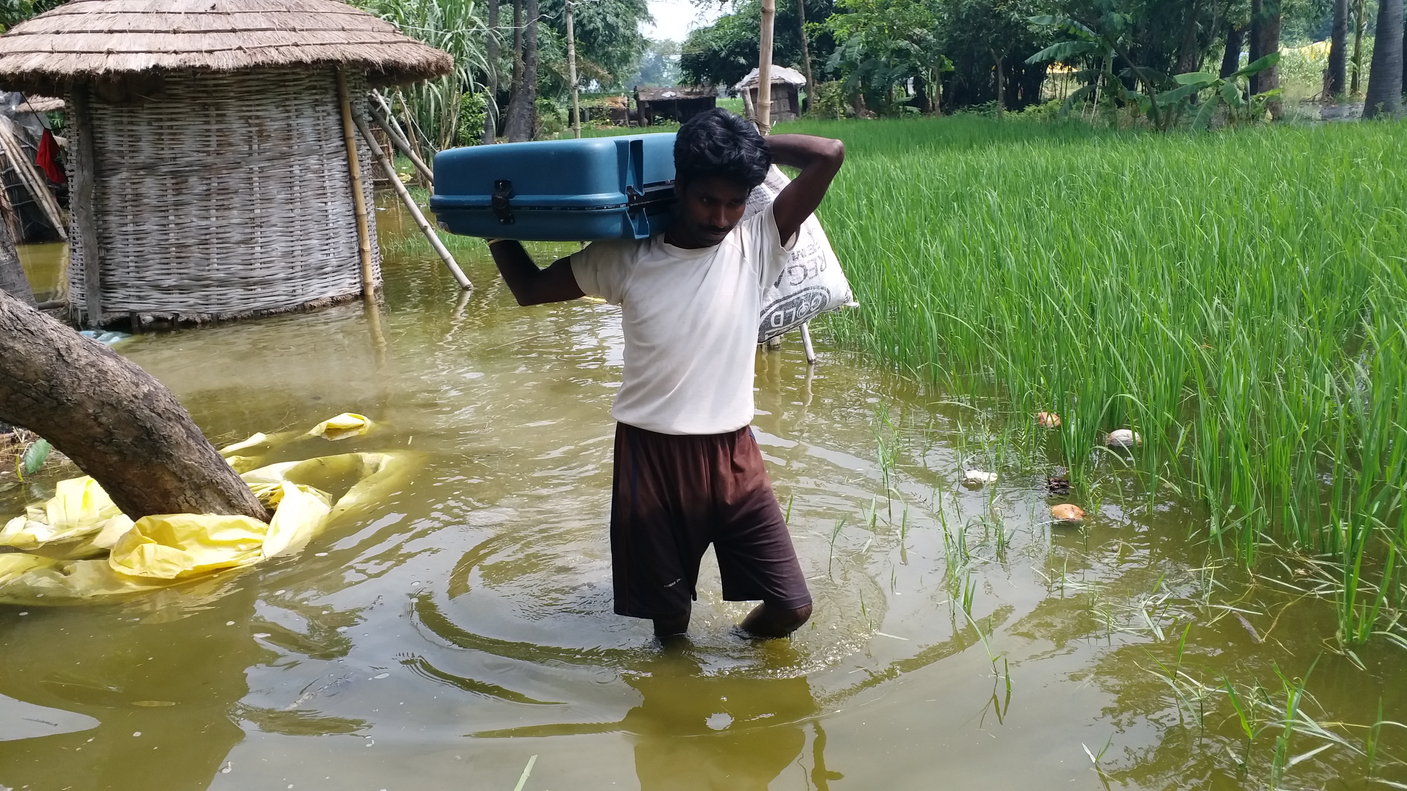 घर से सामान निकालता बाढ़ पीड़ित