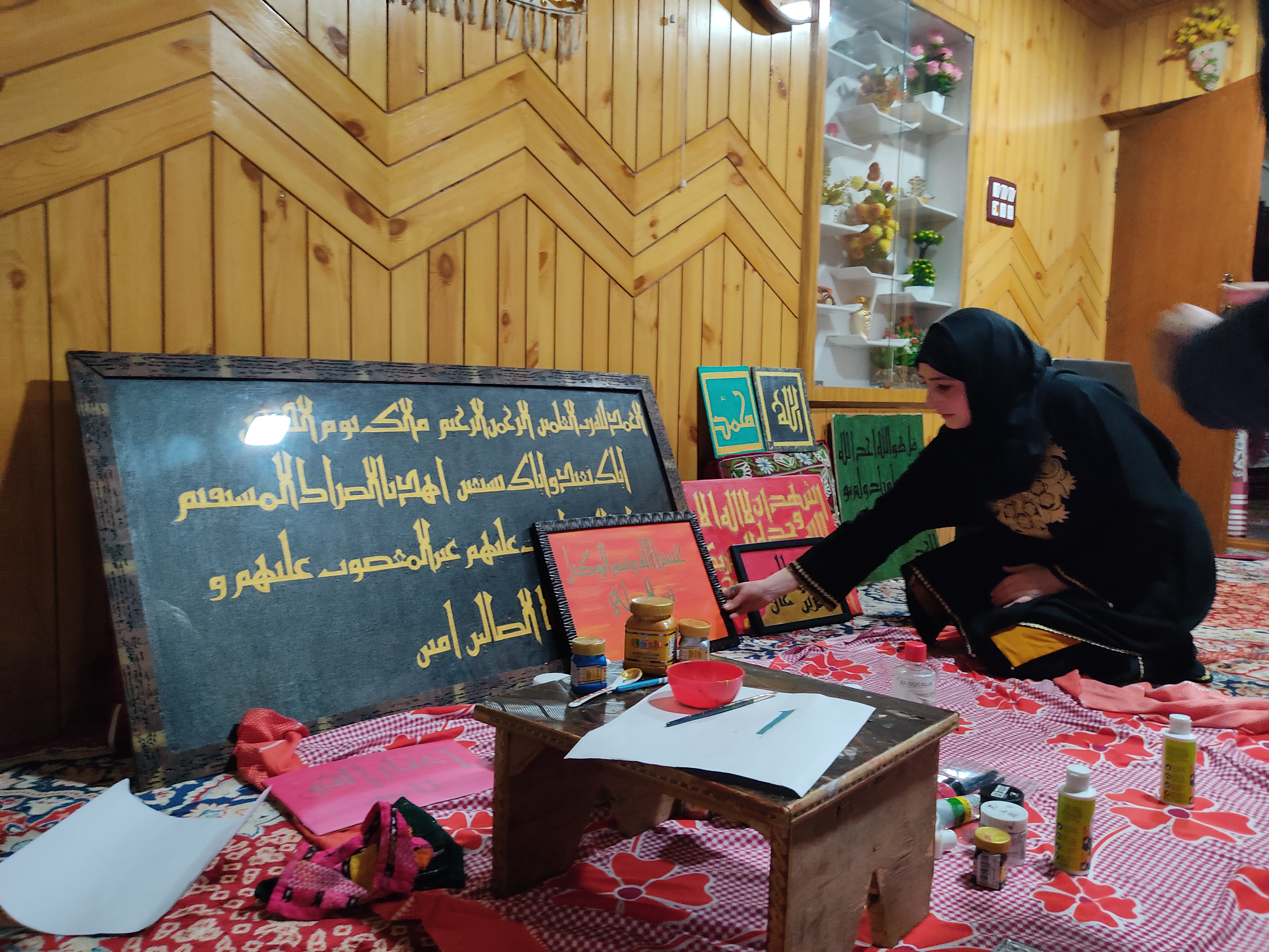 Calligrapher Farah Deeba while writing on the painting walls