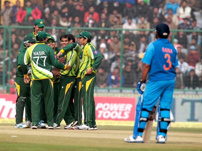 Victorious Pakistan team celebrate as Indian batsman Suresh Raina looks on in 2012-13.