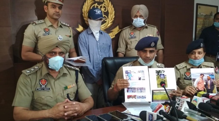 Mohali SSP Kuldeep Singh Chahal displays the laptops, mobile phones and documents sized with Ravinder Singh Dandiwal (in blue shirt) standing behind him.