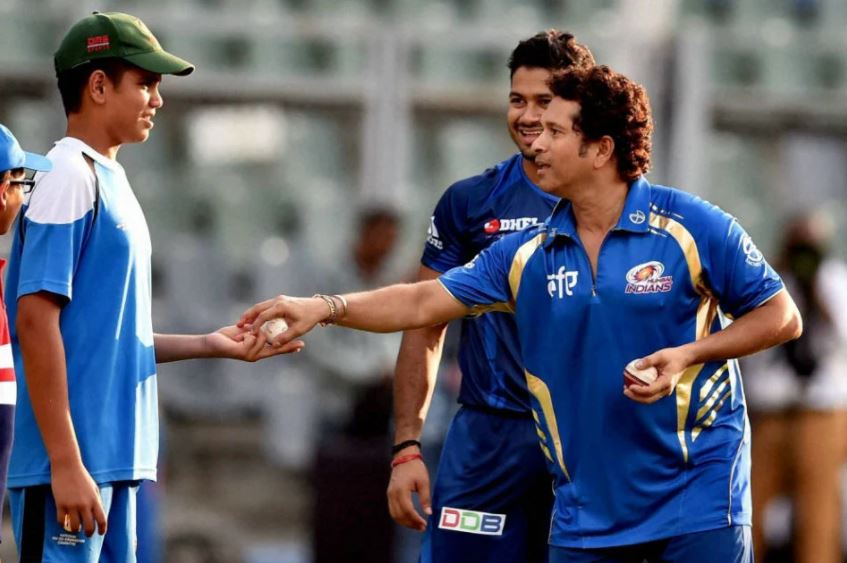 Sachin Tendulkar handing over a white ball to his son Arjun Tendulkar during an IPL net session.