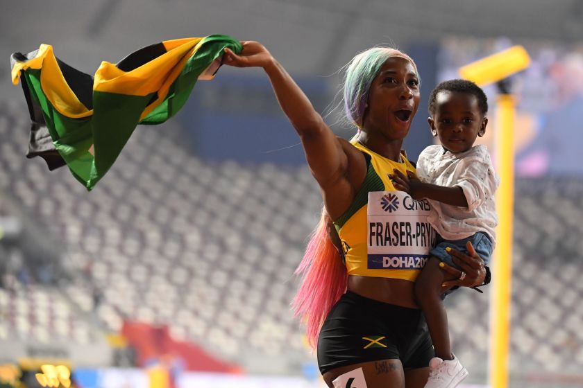 Shelly-Ann Fraser-Pryce of Jamaica punches in the air with her son after winning her fourth World Championships gold in 100m race.