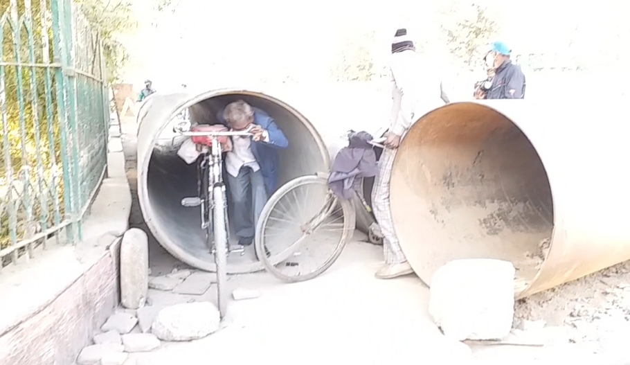 bikes and cyclists pass through narrow pipes in agra