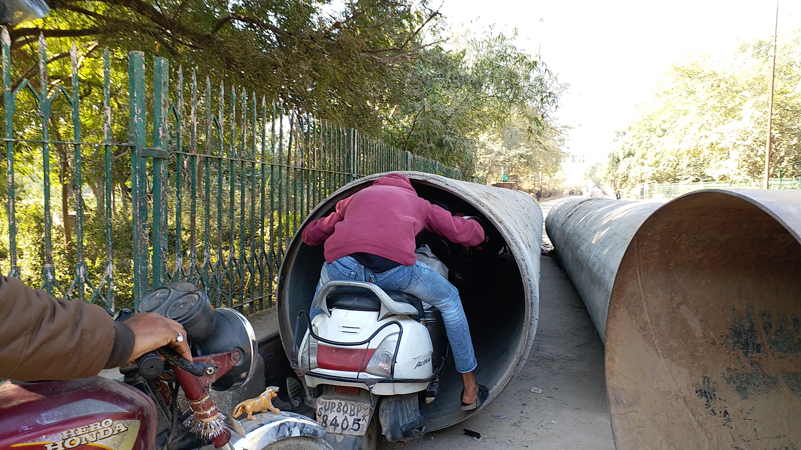 bikes and cyclists pass through narrow pipes in agra