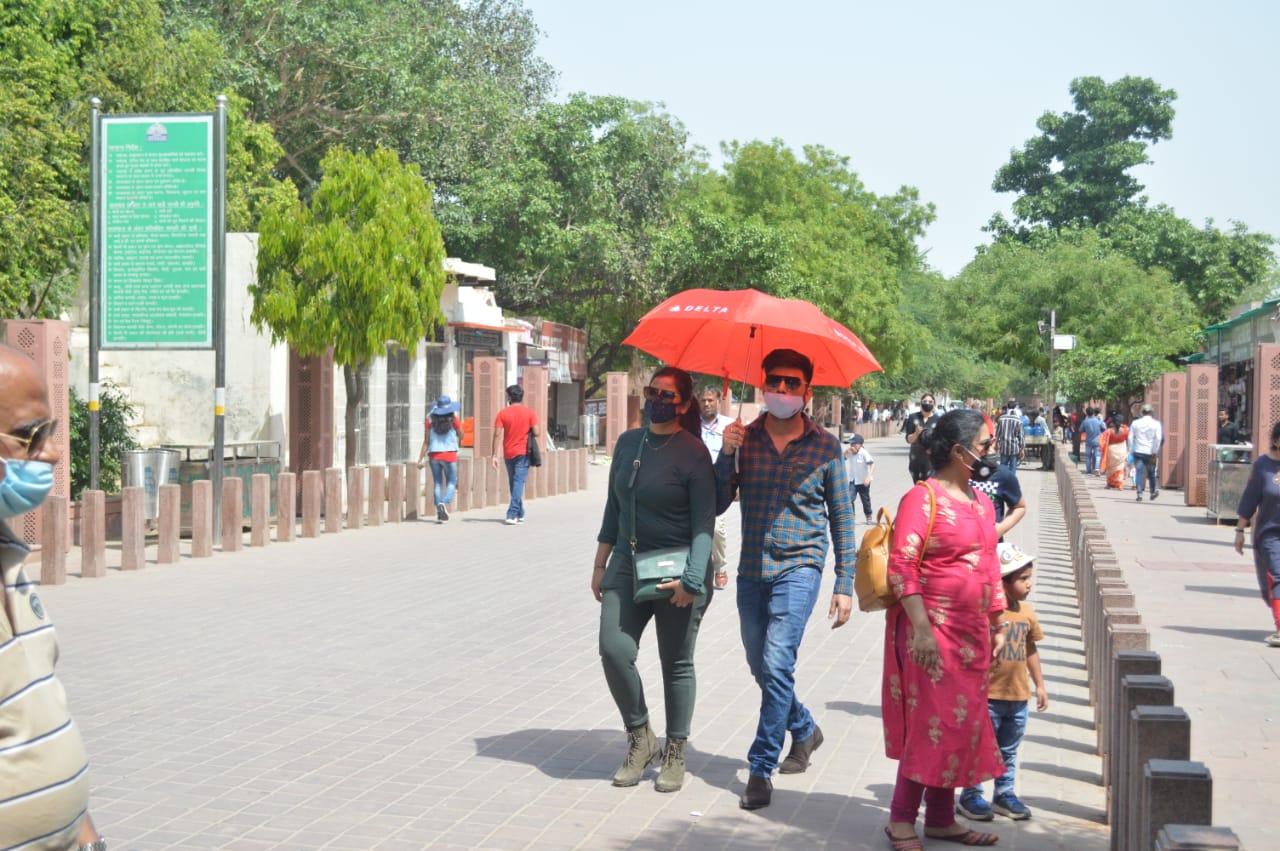 तेज धूप से बचने के लिए छाता लगा कर जाते पर्यटक.