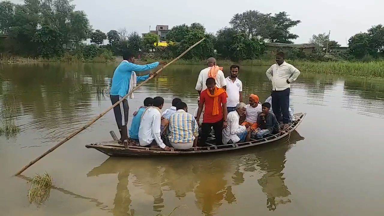 नाव के सहारे नदी का तट पार करते ग्रामीण