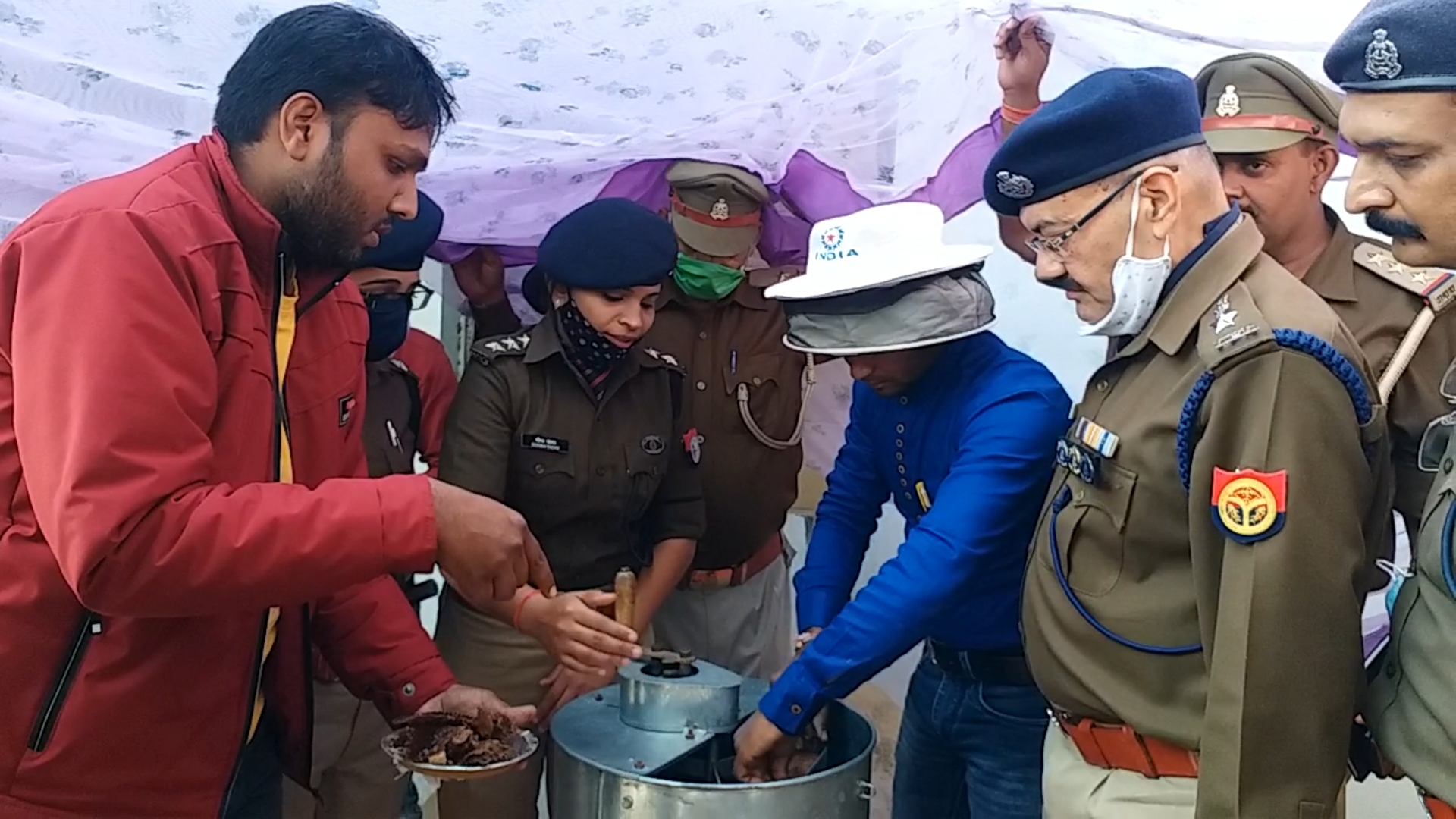 शहद निकालते कर्मचारी के साथ पुलिसकर्मी.