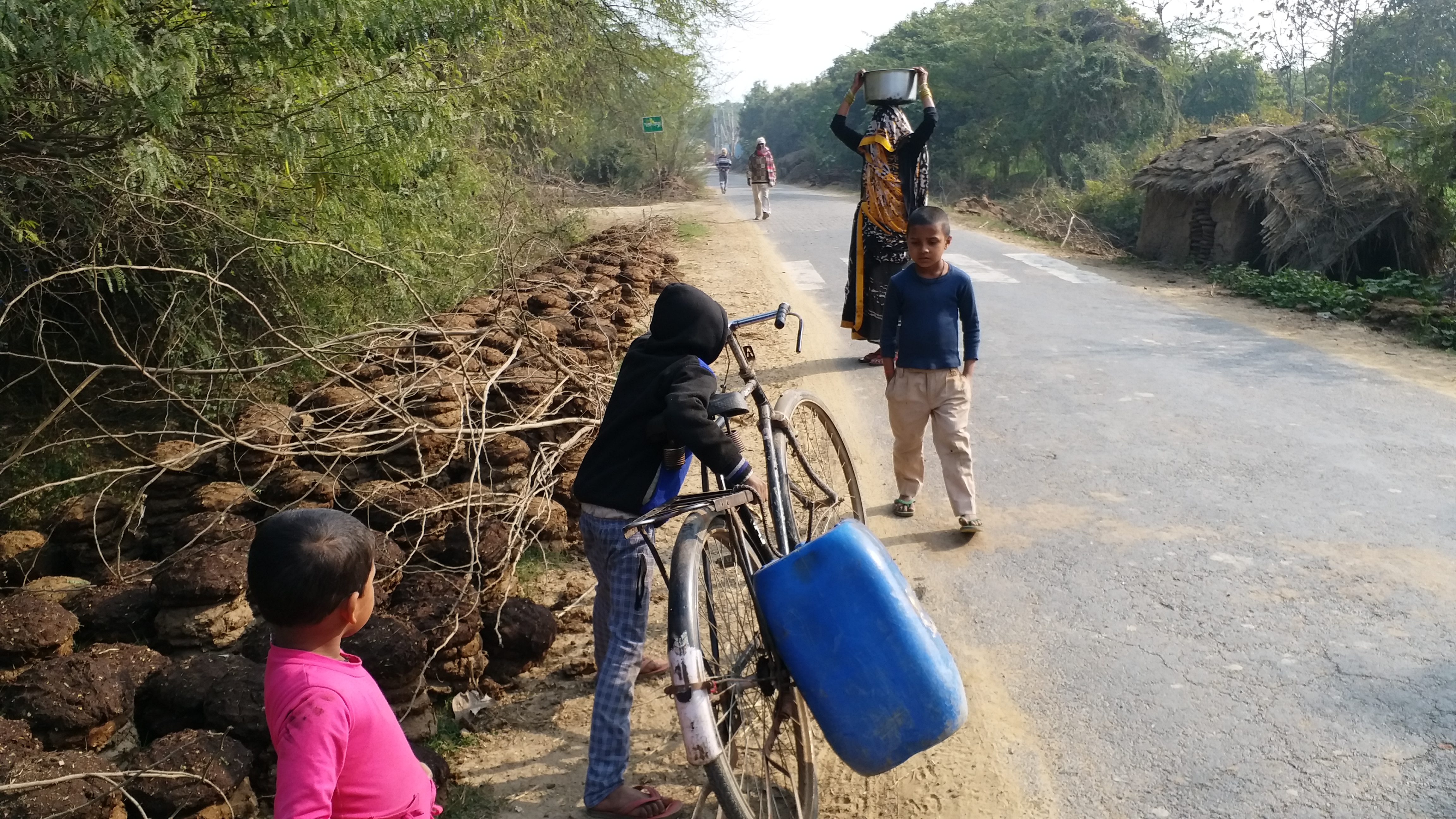 साइकिल पर पानी का डिब्बा लेकर जाते बच्चे.