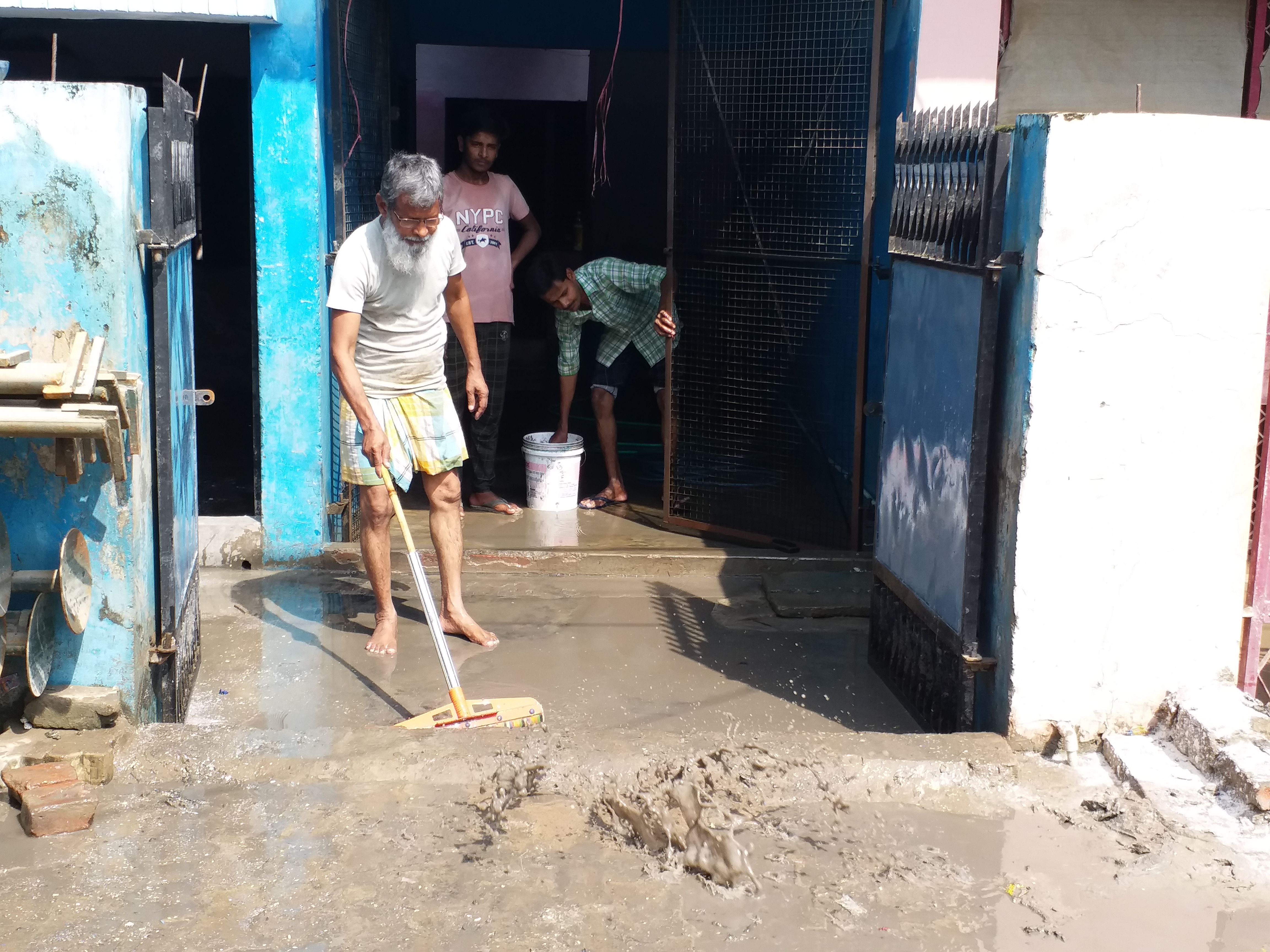 घरों से जमा कीचड़ हटाते लोग.