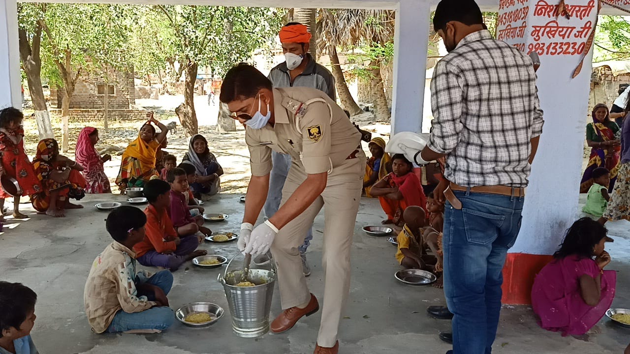 लोगों के बीच भोजन परोसते थानाध्यक्ष