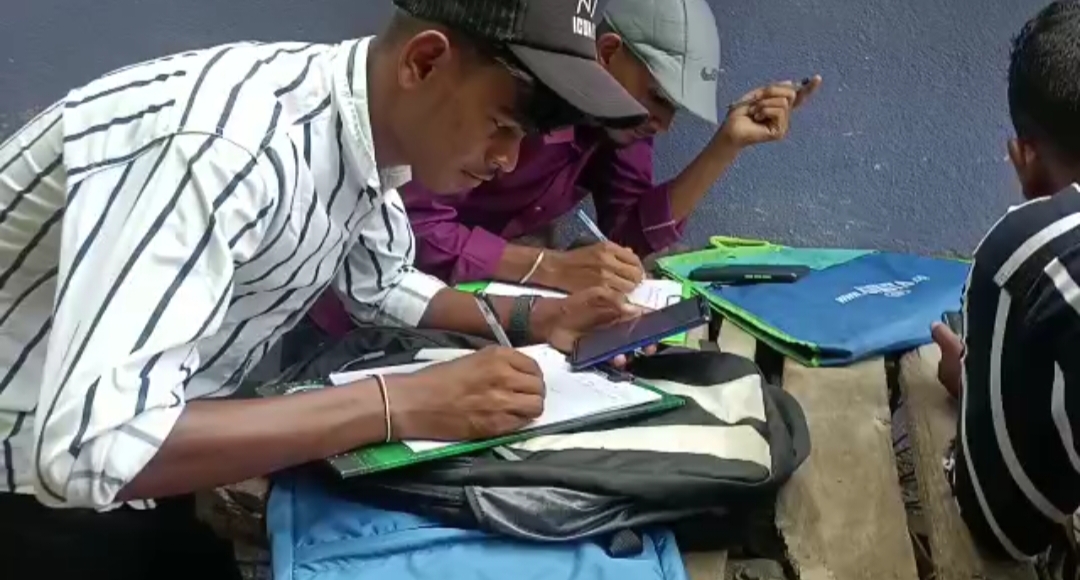 Students writing answer sheet seeing mobile or book in Surendranath College at Raiganj